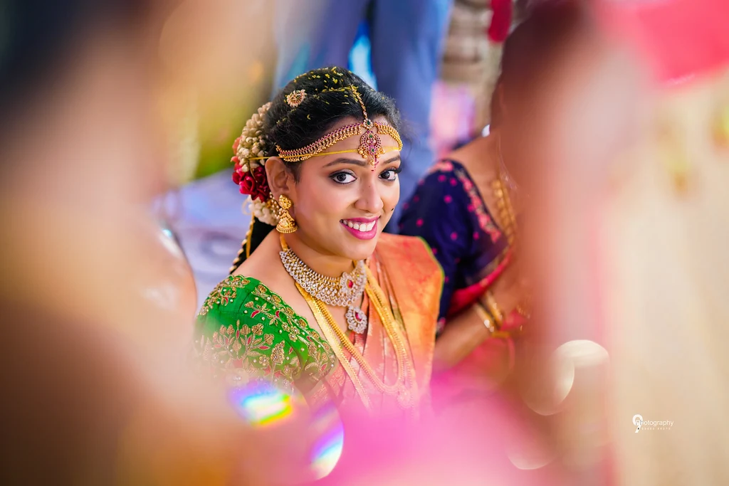 A bride in green and gold framed by warm foreground light