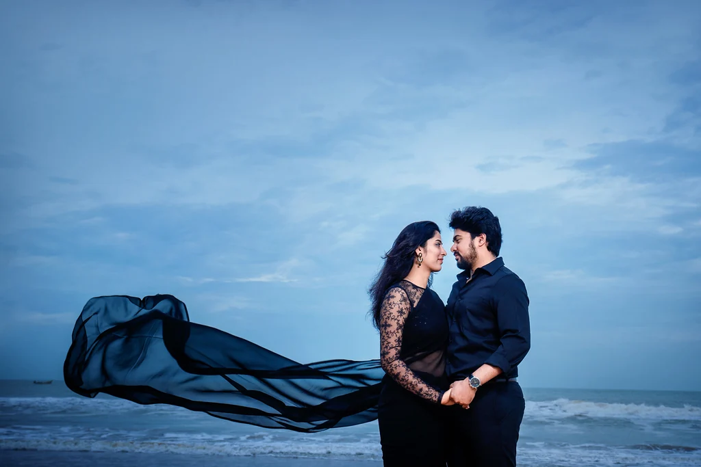 A couple embracing by the sea, with a black scarf in the breeze