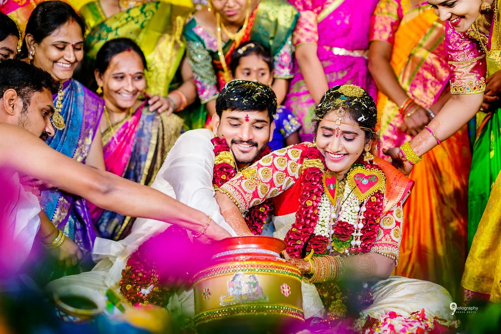 A laughing couple surrounded by family during a wedding ritual