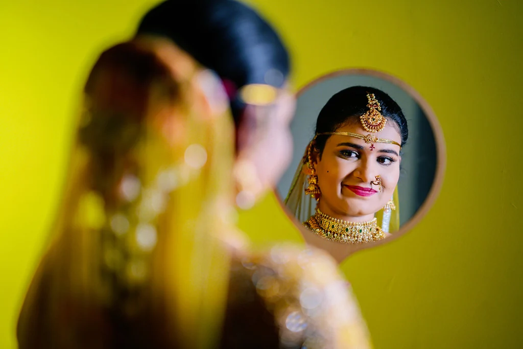 A bride reflected in a small mirror while preparing for her wedding